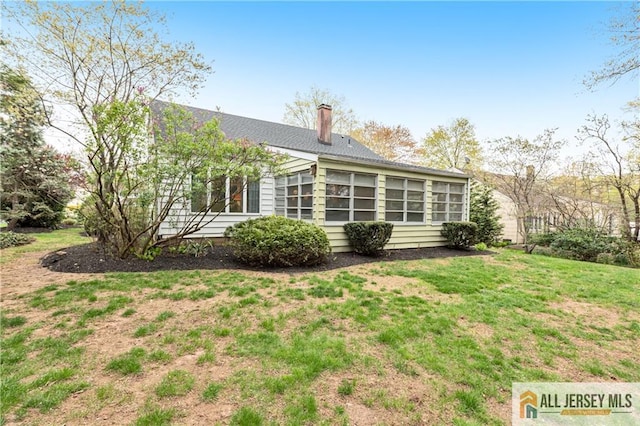 back of house featuring a lawn and a chimney