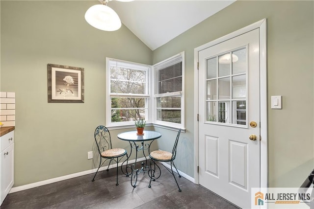 dining space featuring baseboards and lofted ceiling