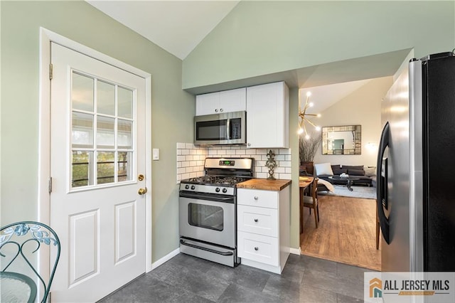 kitchen with white cabinets, appliances with stainless steel finishes, wooden counters, and vaulted ceiling