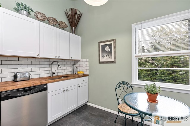 kitchen featuring decorative backsplash, wooden counters, baseboards, a sink, and dishwasher