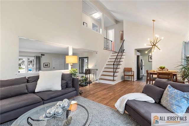 living area featuring visible vents, wood finished floors, stairway, high vaulted ceiling, and a chandelier