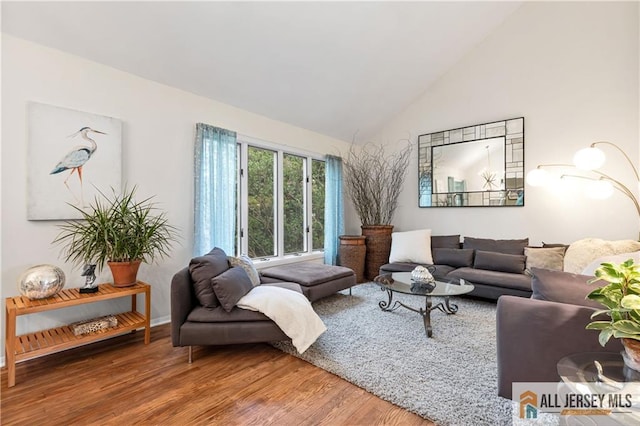 living room featuring high vaulted ceiling, baseboards, and wood finished floors
