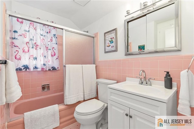 full bath featuring vanity, toilet, tile walls, combined bath / shower with glass door, and vaulted ceiling