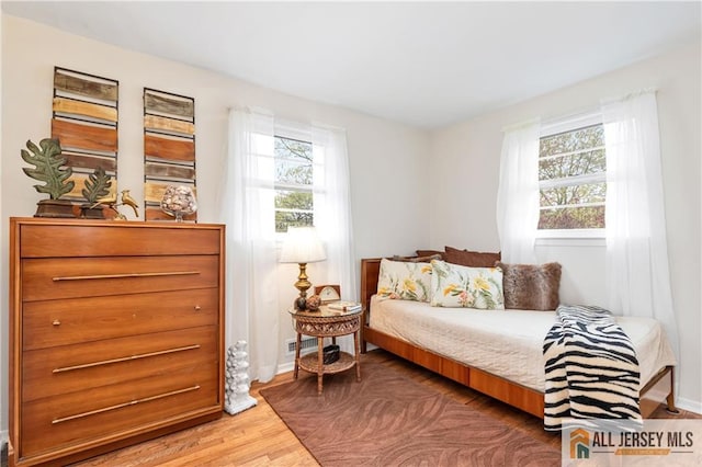 bedroom with baseboards, wood finished floors, and visible vents