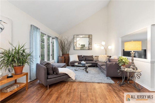 living room with wood finished floors and high vaulted ceiling