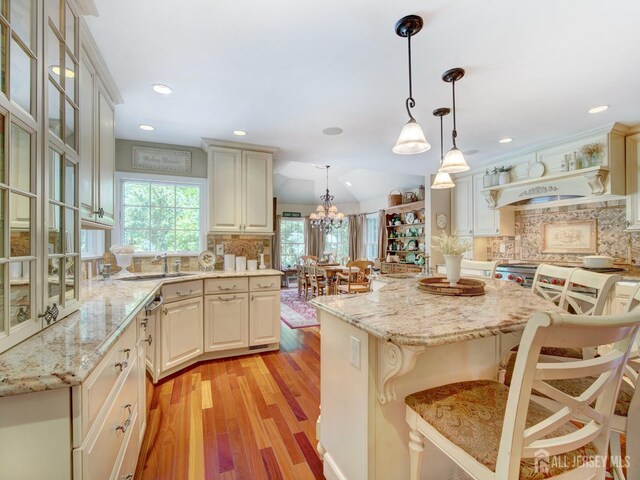 7 Willis Ct, East Brunswick, NJ 08816 - kitchen with light wood-style floors, backsplash, light stone countertops, a kitchen bar, and recessed lighting