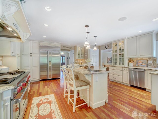 7 Willis Ct, East Brunswick, NJ 08816 - kitchen with premium appliances, premium range hood, light wood-style flooring, backsplash, and glass insert cabinets