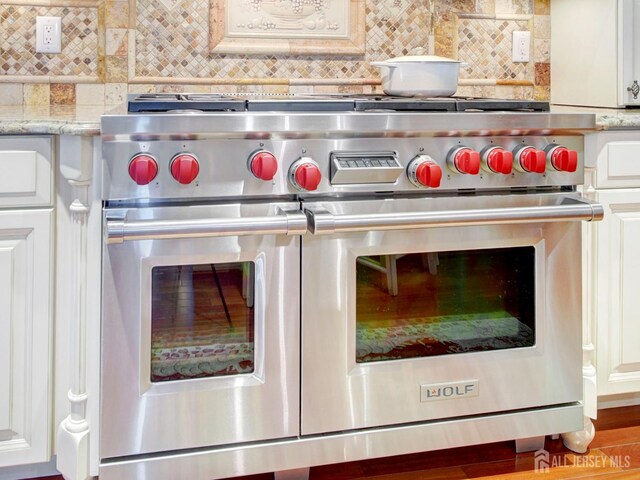7 Willis Ct, East Brunswick, NJ 08816 - detailed view of premium stove, decorative backsplash, white cabinets, and light stone counters