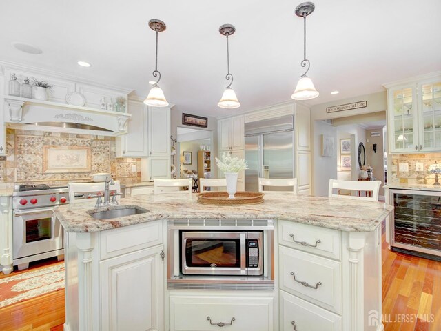 7 Willis Ct, East Brunswick, NJ 08816 - kitchen with wine cooler, high quality appliances, backsplash, light wood-type flooring, and white cabinetry