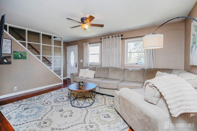 living room with baseboards, ceiling fan, stairway, and wood finished floors