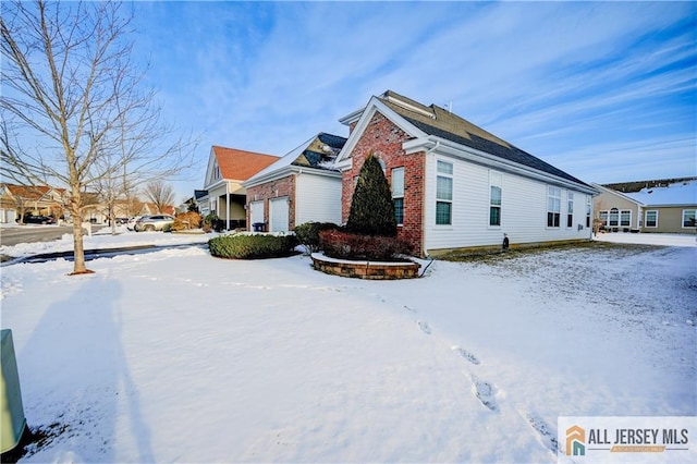 snow covered property featuring brick siding