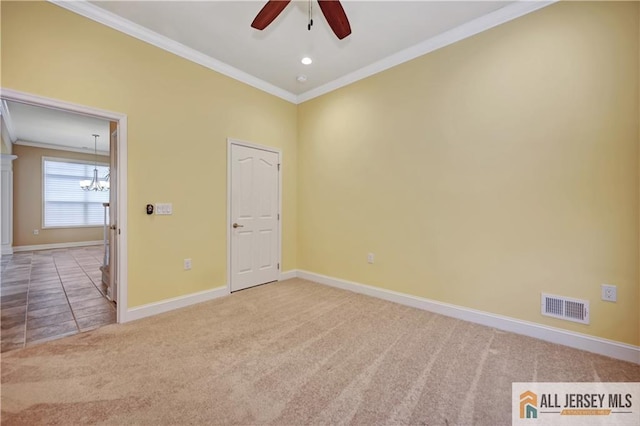 carpeted spare room with ceiling fan with notable chandelier, baseboards, visible vents, and ornamental molding