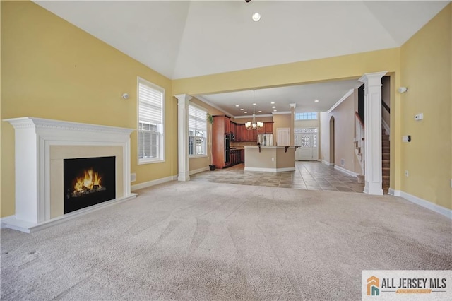 unfurnished living room featuring decorative columns, light carpet, a lit fireplace, and ornamental molding