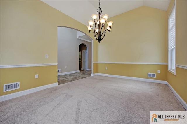 empty room with visible vents, arched walkways, carpet flooring, a chandelier, and vaulted ceiling