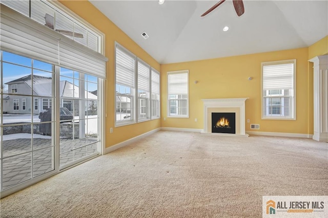 unfurnished living room featuring plenty of natural light, visible vents, a ceiling fan, and a lit fireplace