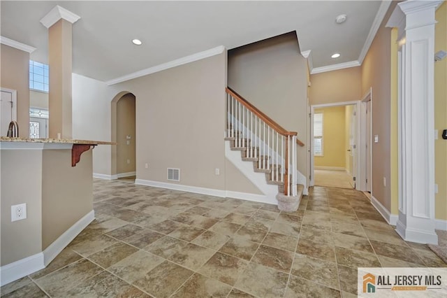 foyer entrance with visible vents, crown molding, baseboards, and decorative columns