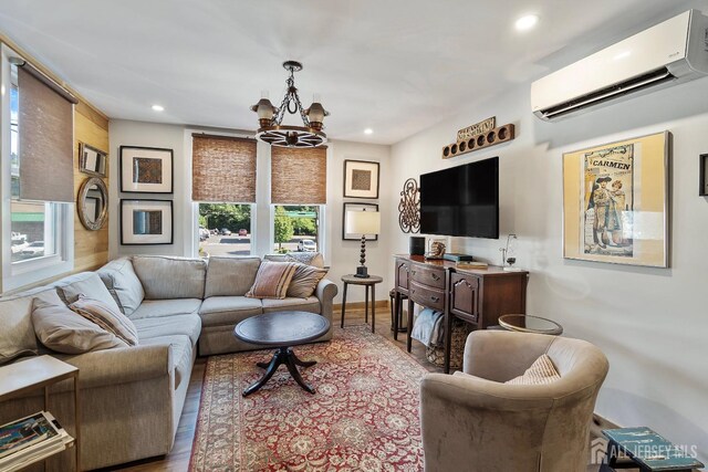 living room featuring light hardwood / wood-style floors, a wall mounted AC, and a notable chandelier