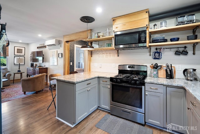 kitchen with kitchen peninsula, stainless steel appliances, gray cabinets, and light stone counters