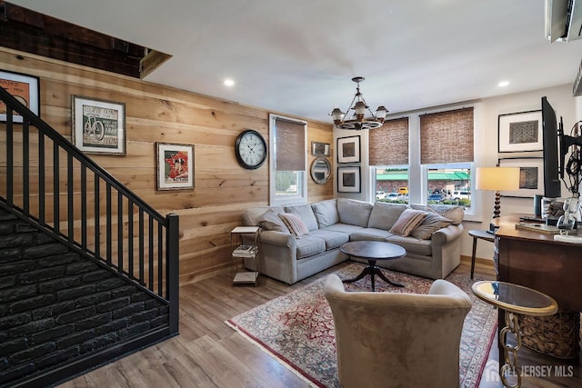 living room with hardwood / wood-style floors, an inviting chandelier, and wooden walls