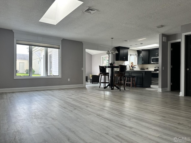 interior space featuring a textured ceiling, a skylight, wood-type flooring, and stainless steel appliances