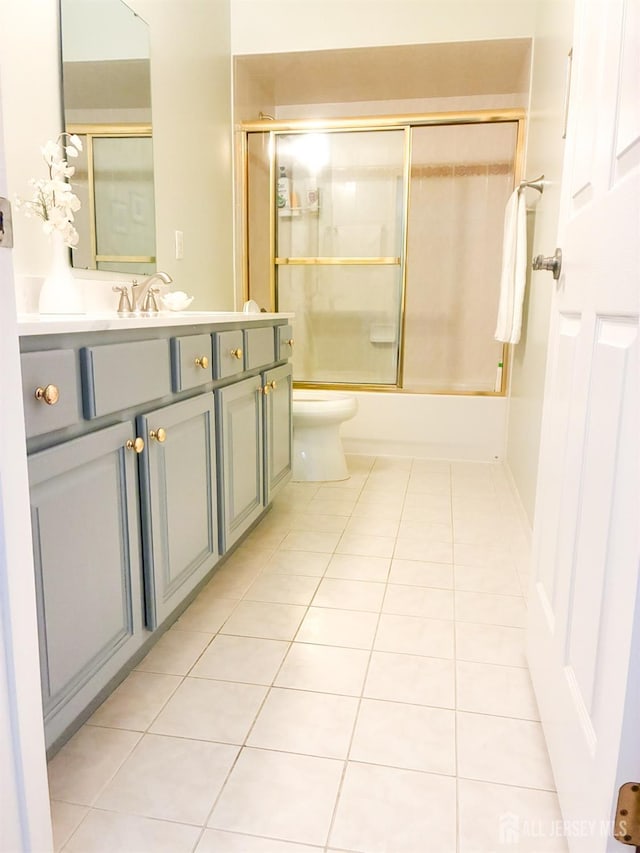 full bath featuring tile patterned floors, toilet, vanity, and combined bath / shower with glass door