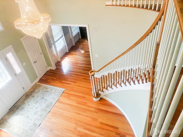 foyer entrance featuring a chandelier, wood finished floors, a high ceiling, and stairway
