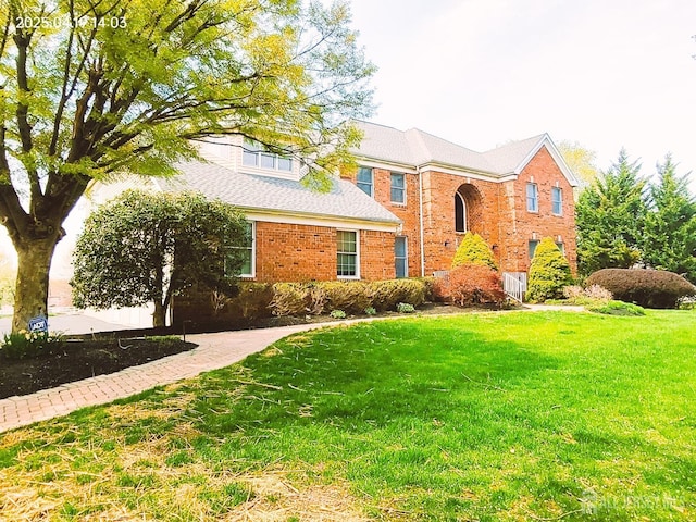 traditional-style home featuring brick siding and a front yard