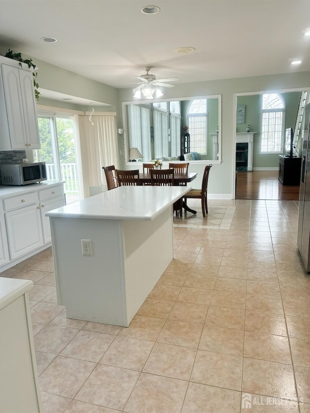 kitchen with stainless steel microwave, light tile patterned floors, white cabinetry, ceiling fan, and recessed lighting