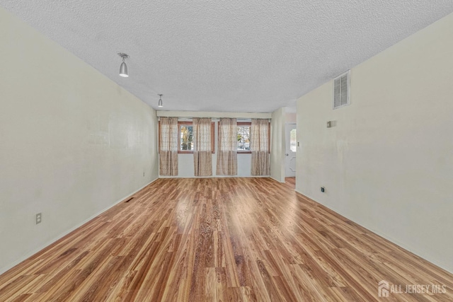 unfurnished living room featuring a textured ceiling and light wood-type flooring