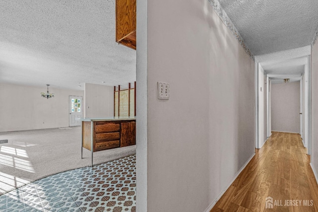 hall with light hardwood / wood-style floors and a textured ceiling