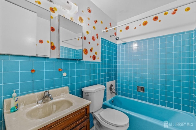 full bathroom with tiled shower / bath, tile walls, vanity, and toilet