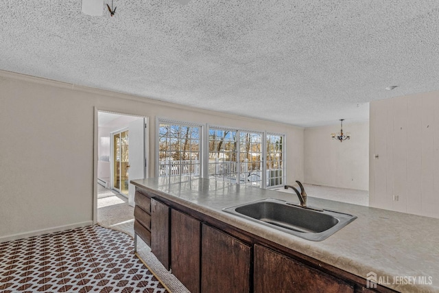 kitchen featuring dark brown cabinets, sink, hanging light fixtures, and a textured ceiling