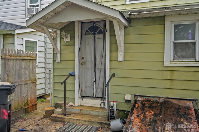 view of exterior entry with cooling unit and fence