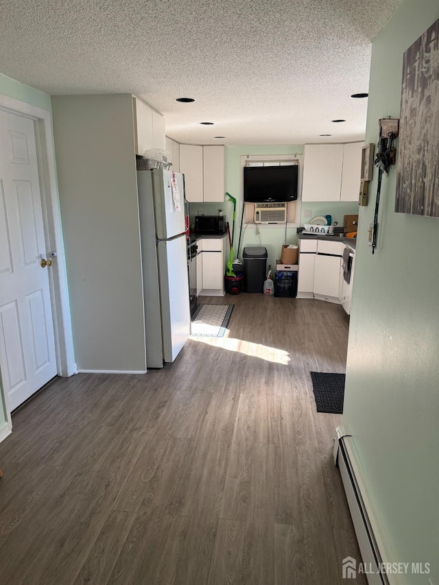 kitchen featuring freestanding refrigerator, dark wood-type flooring, white cabinets, dark countertops, and baseboard heating