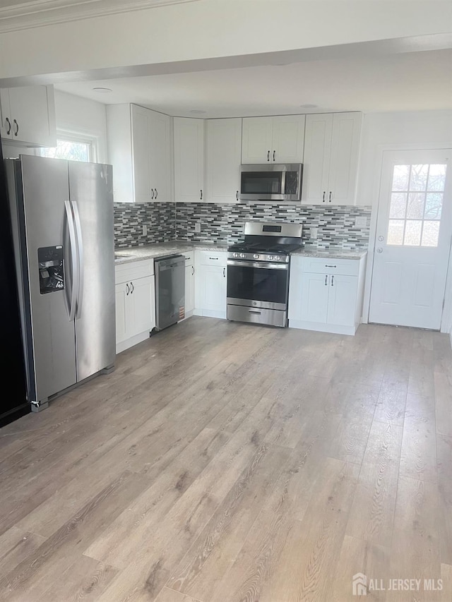 212 Huff Ave, Manville, NJ 08835 - kitchen featuring stainless steel appliances, light countertops, decorative backsplash, light wood finished floors, and white cabinetry