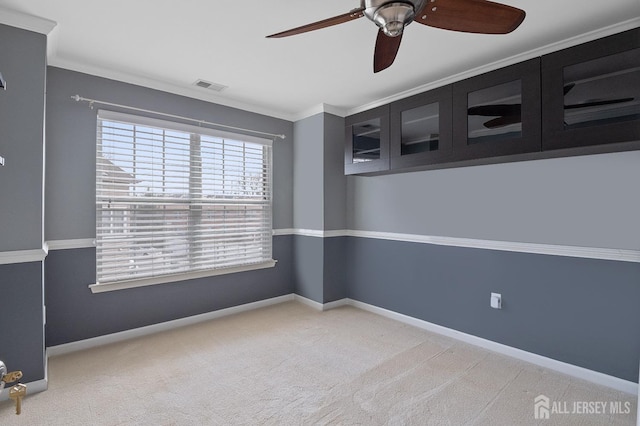 spare room featuring visible vents, carpet flooring, baseboards, and ornamental molding