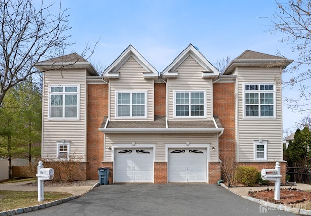 townhome / multi-family property with brick siding, driveway, an attached garage, and roof with shingles