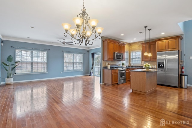 kitchen featuring brown cabinets, dark countertops, appliances with stainless steel finishes, and open floor plan