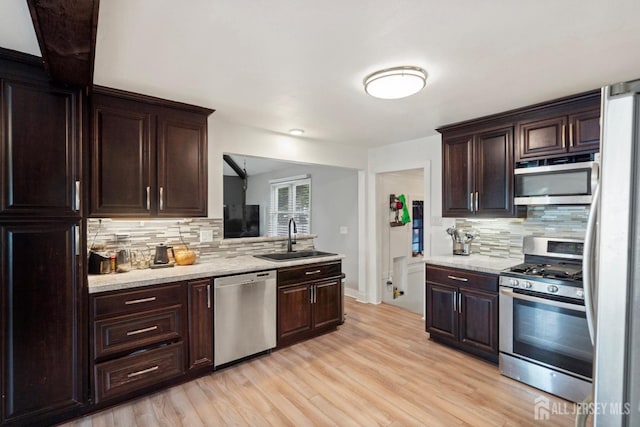 kitchen featuring light wood-type flooring, sink, appliances with stainless steel finishes, and tasteful backsplash