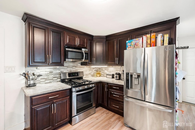 kitchen featuring light stone countertops, appliances with stainless steel finishes, light hardwood / wood-style floors, and tasteful backsplash