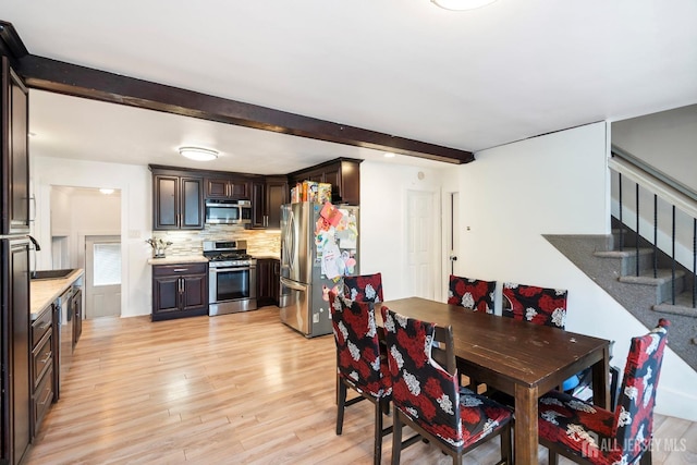 dining area with beam ceiling, light hardwood / wood-style floors, and sink