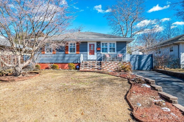 ranch-style house with aphalt driveway, a front yard, and a porch