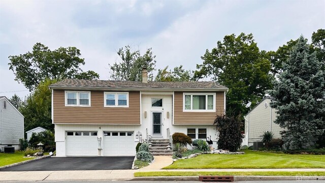 split foyer home with cooling unit, a garage, and a front yard