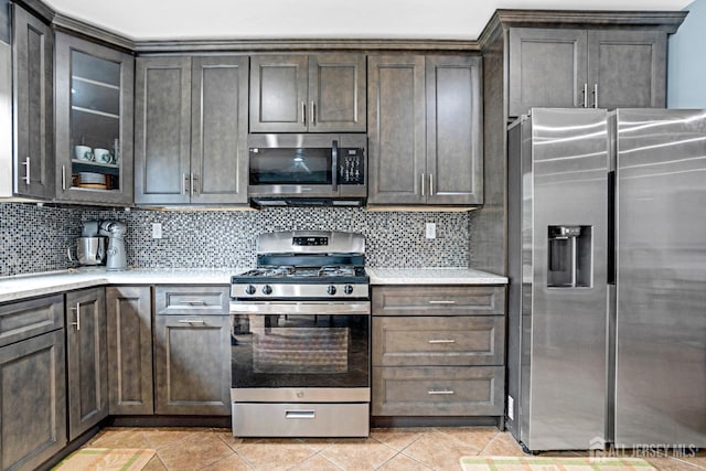 kitchen featuring light countertops, decorative backsplash, stainless steel appliances, and light tile patterned floors