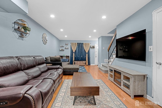 living area featuring radiator heating unit, light wood-style floors, stairway, and recessed lighting
