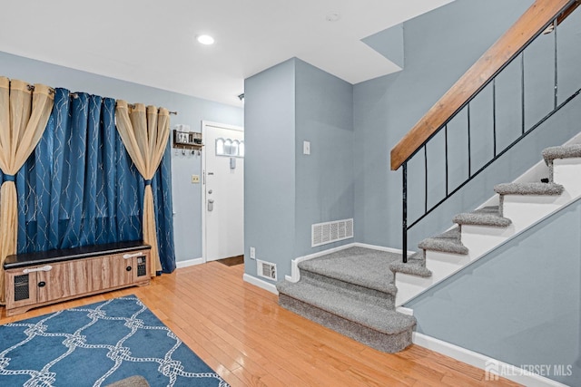 entrance foyer featuring hardwood / wood-style flooring, stairs, baseboards, and visible vents