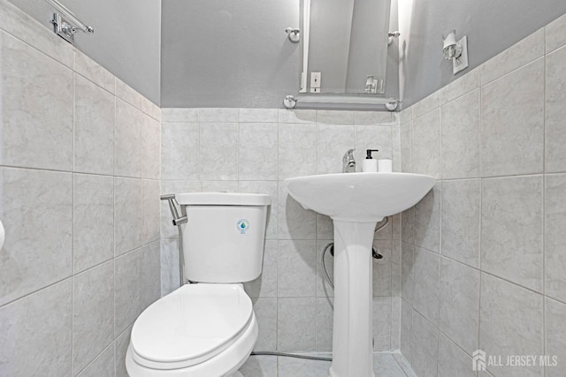 bathroom with tile walls and toilet