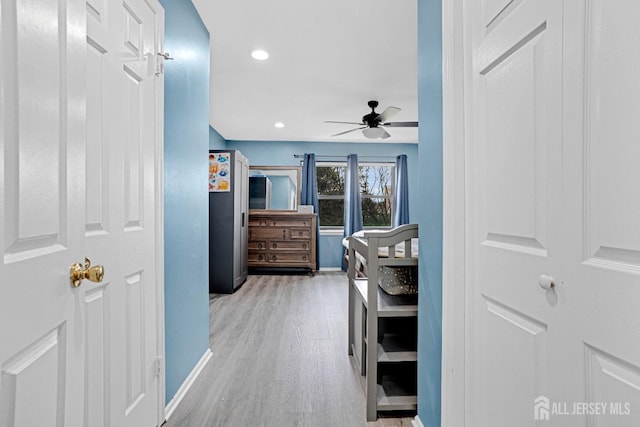 corridor with light wood finished floors, baseboards, and recessed lighting