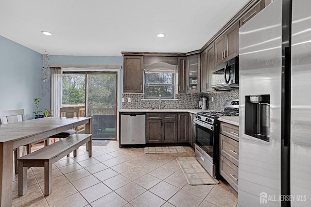 kitchen featuring a sink, dark brown cabinetry, decorative backsplash, light countertops, and appliances with stainless steel finishes
