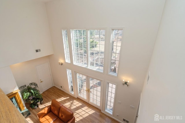 living room featuring wood finished floors, visible vents, and a towering ceiling